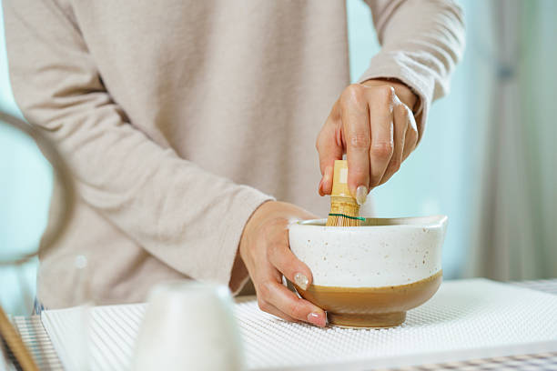 istock Asian woman preparing traditional Japanese matcha tea at home using bamboo tools, sifting matcha powder with care and precision. 2232614739