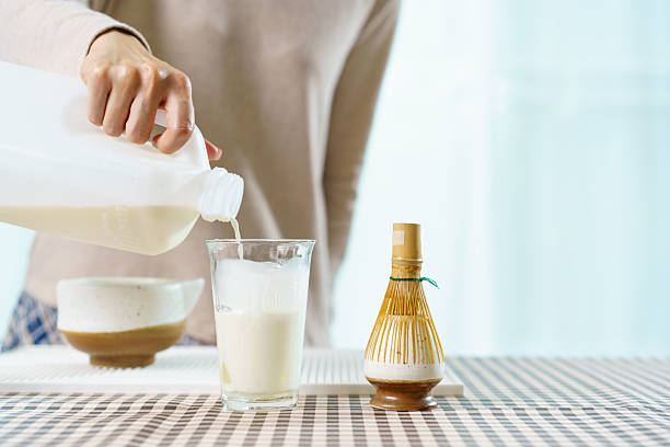 istock Asian woman preparing traditional Japanese matcha tea at home using bamboo tools, sifting matcha powder with care and precision. 2232614794