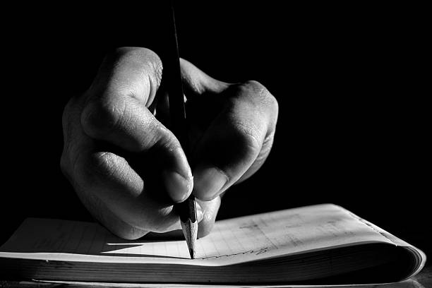 Close Up of Hand Writing with Pencil on Notebook in Black and White
