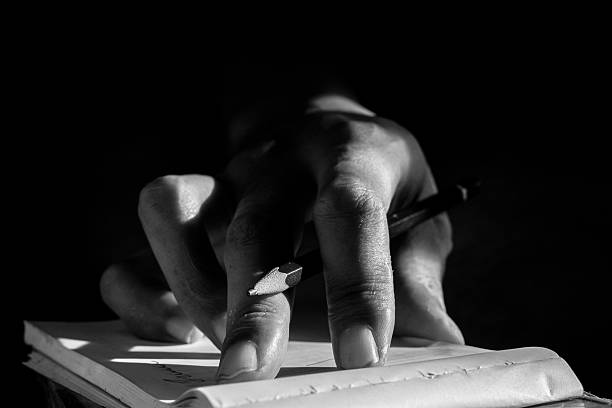 istock Close Up of Hand Writing with Pencil on Notebook in Black and White 2232618927