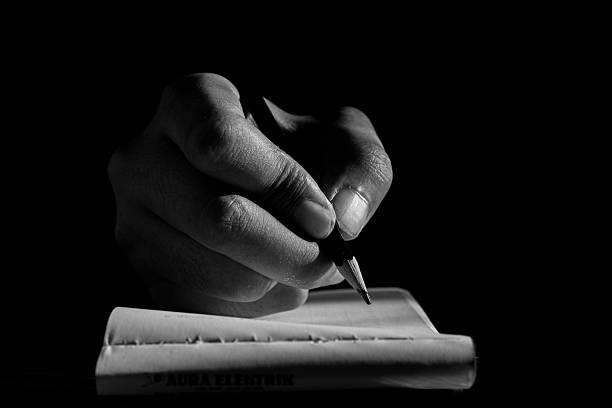 Close Up of Hand Writing with Pencil on Notebook in Black and White