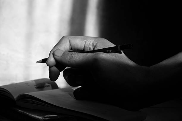 istock Close Up of Hand Writing with Pencil on Notebook in Black and White 2232619055