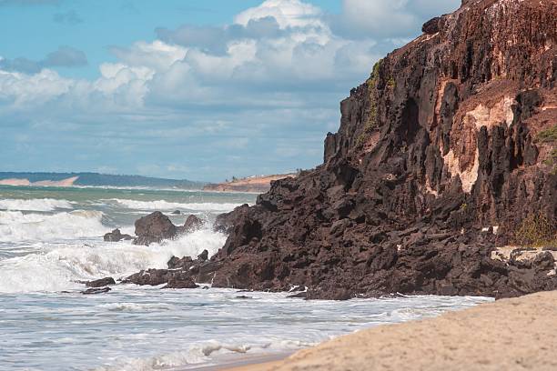 istock Scenic view of rocky cliffs meeting ocean waves under a partly cloudy sky 2232626345
