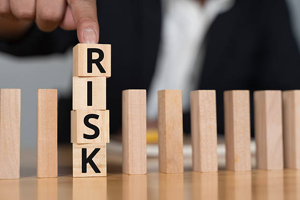 istock Risk management concept with hand placing wooden blocks spelling risk, preventing falling domino effect 2232628464