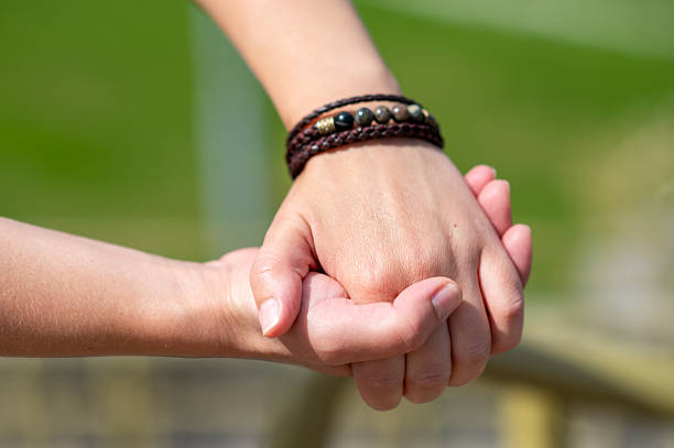 Close-up of two hands clasped together, symbolizing love, trust, and emotional connection