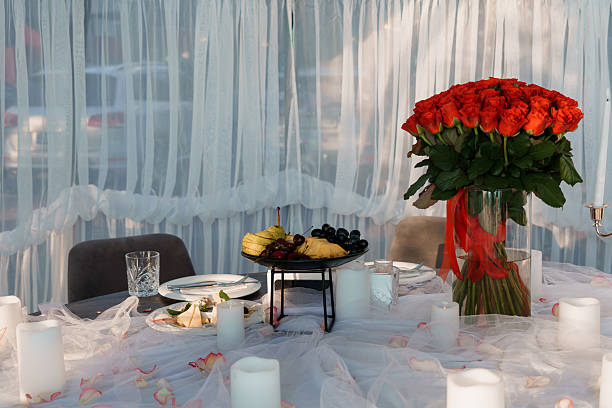 istock Romantic Dinner Setting with Red Roses, Fruit Platter, Candlelight, Sheer Curtains, and Elegant Table Decor, Luxurious Mood. 2232637603
