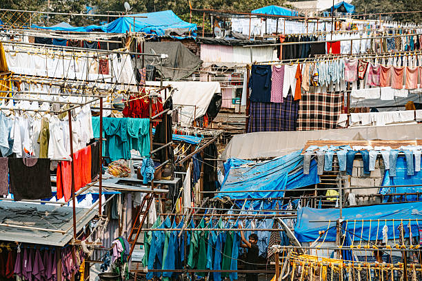 Outdoor laundry system in Mumbai featuring colorful clothes hanging on lines amidst bustling structures. Dhobi Ghat is a open air laundry in Mumbai city.