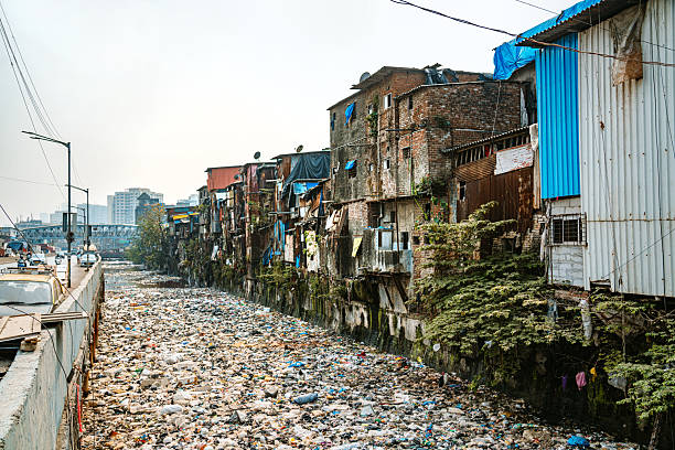 A striking depiction of a polluted river passing through a vibrant, crowded urban area featuring slums in Mumbai, highlighting environmental challenges and local lifestyle. Mumbai Slum, India