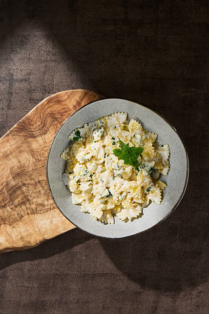 Farfalle quattro formaggi pasta under moody lighting, overhead composition on rustic surface