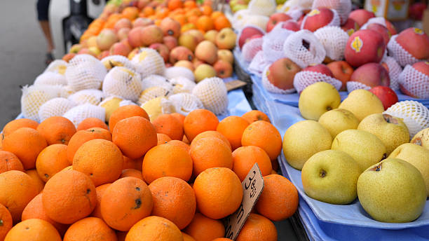 Fresh oranges, pears, and apples on display at fruit stall