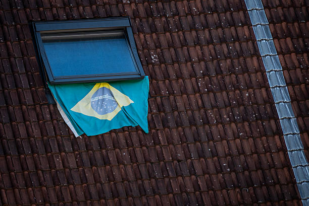 Brazilian flag hanging from a rooftop window on a tiled roof