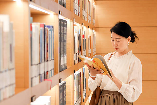 istock An Asian woman reading a book in the library 2232647999