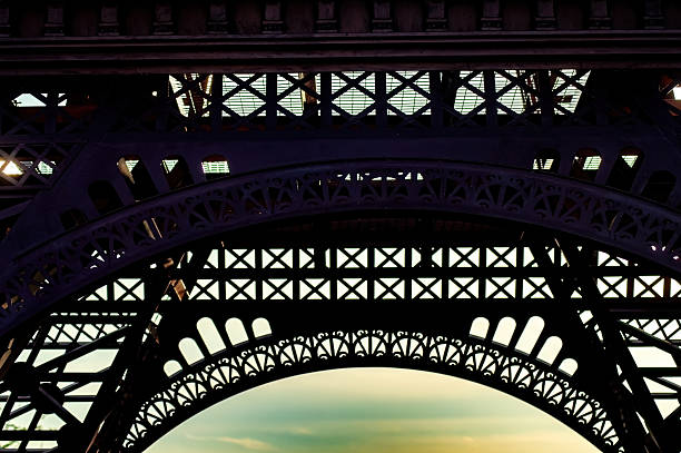 Detailed view of the eiffel tower ironwork against the sky. The architectural details and structural design showcase the iconic landmark engineering.