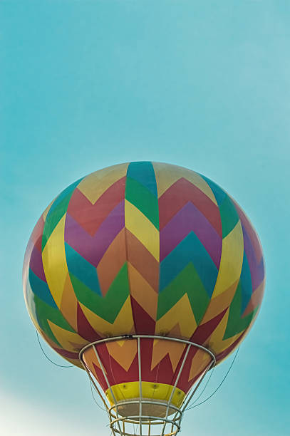Vibrant hot air balloon with a colorful zig zag pattern against a clear blue sky, creating a sense of adventure, travel, and celebration on a bright sunny day.