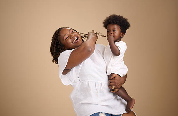A smiling mother embraces her cheerful toddler in a studio portrait.