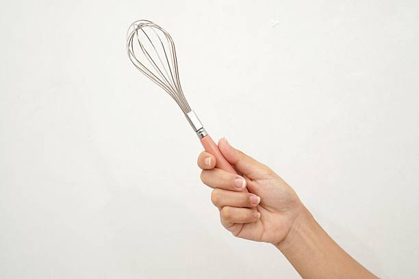 istock Isolated egg beater holding by female hand on white background. Silicone beater with plastic handle. 2232654490