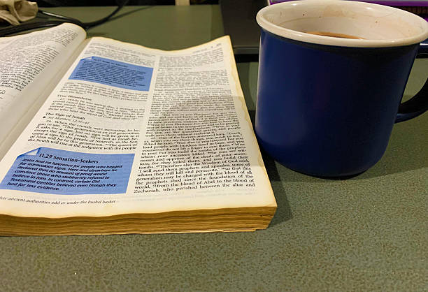 opened bible lay flat on the table with a cup of cholocate on the side