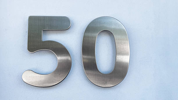 istock Shiny brushed metal house number 50 on light blue wall 2232655770