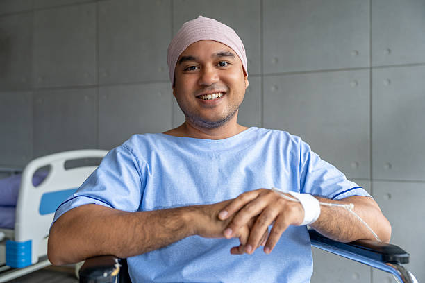 A male cancer patient in a wheelchair with an IV smiles with joy and hope showing strength and positivity during treatment. Man receiving IV therapy in a wheelchair appears happy and uplifted stock photo