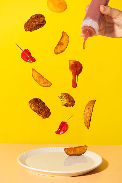 istock Floating potato wedges, nuggets and ketchup on yellow background 2232658131