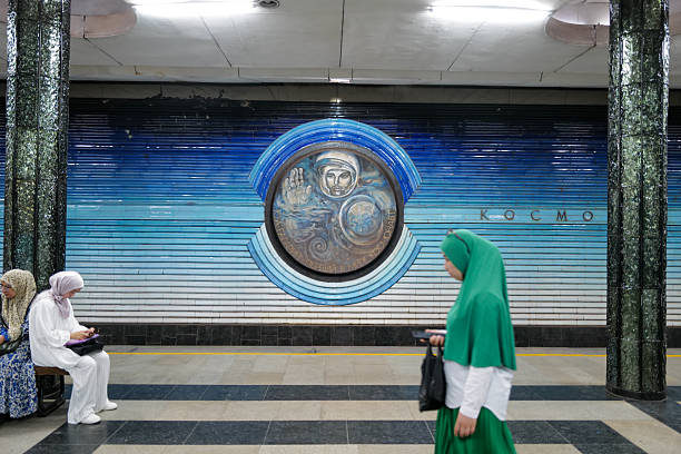 Tashkent, Uzbekistan – August 4, 2025: People wait for trains in the famous Kosmonavtlar Metro Station, a popular tourist attraction known for its spectacular space-themed design dedicated to Soviet cosmonauts, featuring blue ceramic medallions, celestial mosaics, and glass stars on the ceiling that create an immersive cosmic atmosphere. Tourists and daily commuters alike admire the unique architectural and artistic elements that make this station a cultural landmark and a must-visit destination in Tashkent.