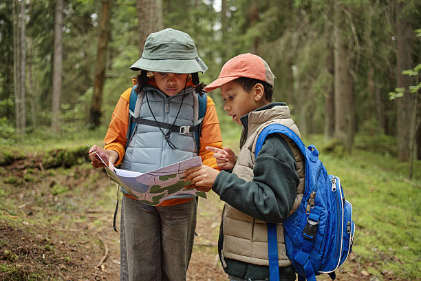istock Two Children Studying Map While Hiking Together in Forest 2232661562