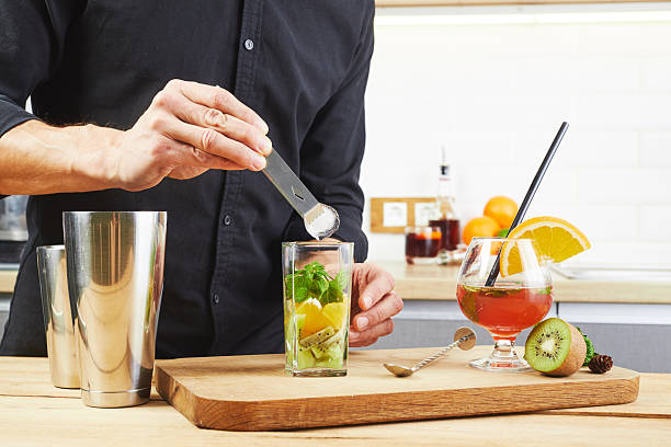 istock An experienced bartender prepares a cocktail at a house party. A man throws ice into a cocktail glass. Making cocktails at home in the kitchen. 2232662530