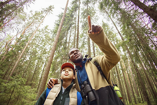 African American Man Guiding Preteen Boy While Exploring Forest Together