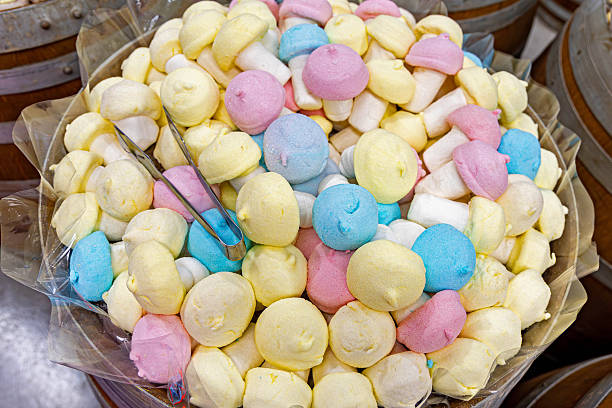 Colorful marshmallow mushrooms in bulk candy bin. Pastel-colored marshmallow candies shaped like mushrooms in a large barrel display, with tongs for self-serve in a candy shop