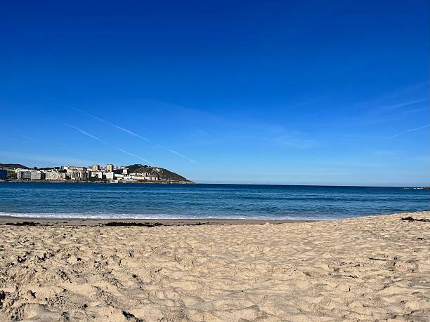 istock Sunny Coastal Beach with Distant City and Blue Sky. 2232666971