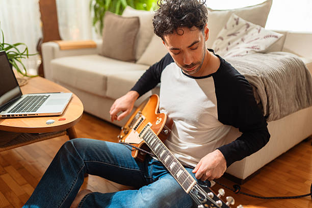 istock Young man tuning electric guitar at home, creative music session, working on new song, remote music production, modern musician lifestyle, home recording setup 2232668942