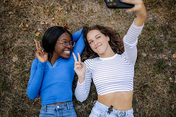 istock Two cheerful female friends taking selfie laying on a grass together 2232670830