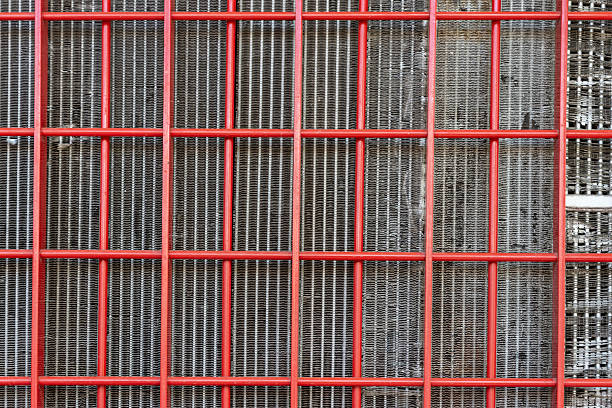 The red metal lattice structure creates intricate intersecting patterns against a gray background. Cooling grille for equipment.