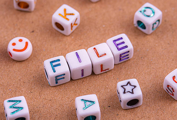 istock White letter beads spelling FILE are arranged on a brown textured surface. 2232677277