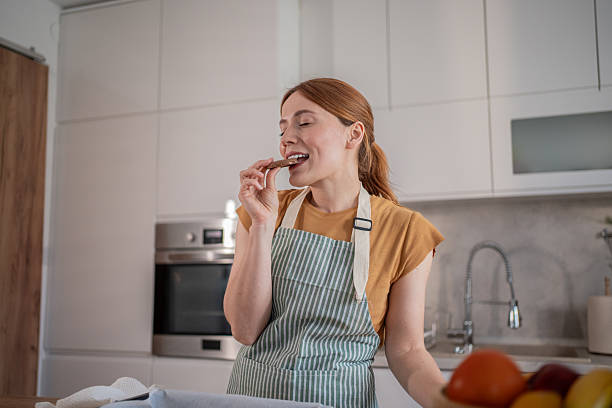 istock Woman tasting a delicious homemade cookie in her modern kitchen 2232677480