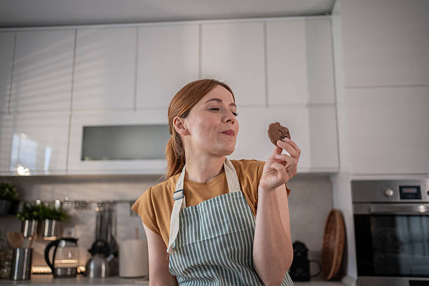 istock Woman looking at a chocolate chip cookie in the kitchen 2232677515
