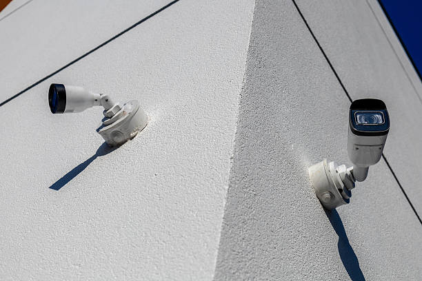 istock Two security cameras mounted on a sharp corner of a white building, capturing activity in the surrounding area during the day 2232680041