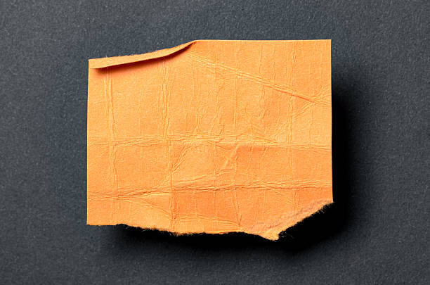 istock One single orange torn ripped wrinkled crumpled blank paper note with drop shadow, folded edge and copy space for text on black background 2232683122