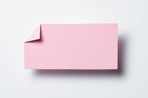 istock Pink paper note cardboard with folded corner dog-ear earmark, drop shadow and copy space for text on white background 2232683518