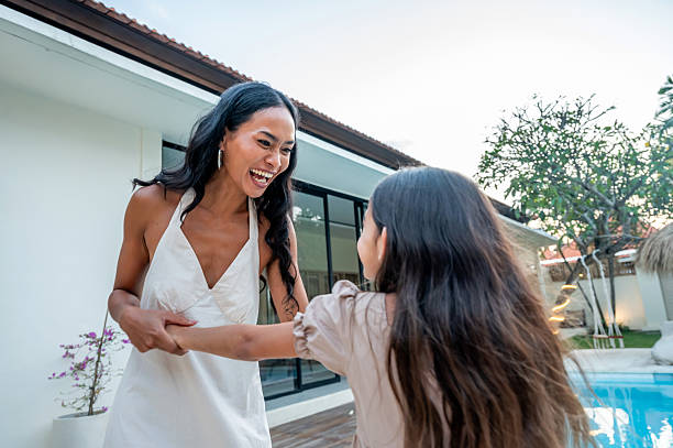 A heartwarming moment between a mother and her daughter, sharing smiles and laughter outdoors near a swimming pool in a cozy and modern home environment, evoking feelings of joy and connection.