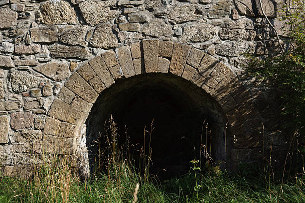 19th-century stone lime kiln in Leszczyniec, Lower Silesia, Poland, stands as an immovable heritage monument with weathered masonry, moss accents, and rustic industrial charm amid verdant surroundings