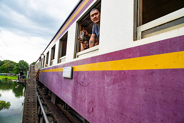 A passenger aboard a train photographing scenic views as it traverses a historical bridge surrounded by nature.