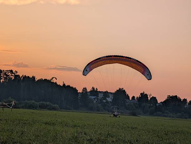 Parachute powered with engine at sunset or sunrise above the sea or ocean.