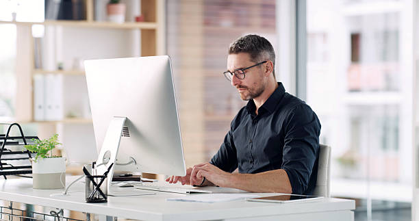 istock Business, man or typing on computer in office for report preparation, auditing or finance proposal. Financial manager, mature person and tech at desk for budget planning and writing compliance email 2232700272