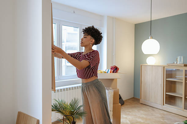 istock Woman arranging framed artwork on wall in new apartment with moving boxes 2232703018