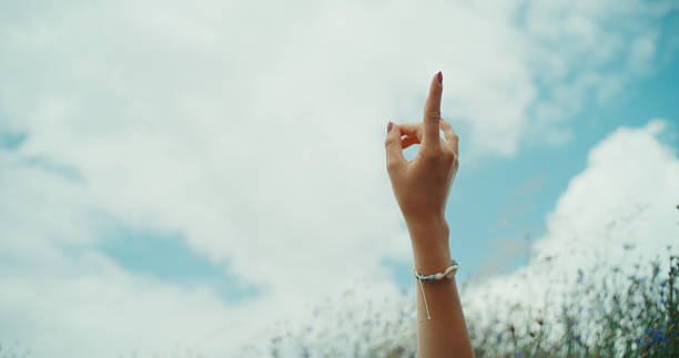Beautiful sunny meadow in the heat of summer. First person view of a person cloudgazing and pointing at the sky