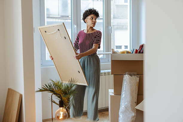 istock Woman arranging artwork at home with boxes during a moving or redecorating session 2232703286
