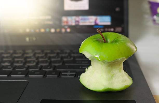 istock A bitten green apple rests on a laptop keyboard with warm light. Office, break time, relaxation concept. 2232711486