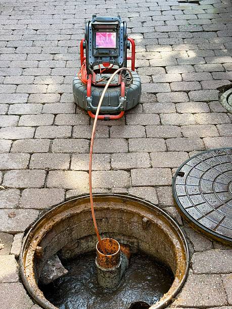A maintenance worker uses a sewer inspection camera to check pipes in a residential building. Concept of plumbing service, pipe repair, and preventive home maintenance.