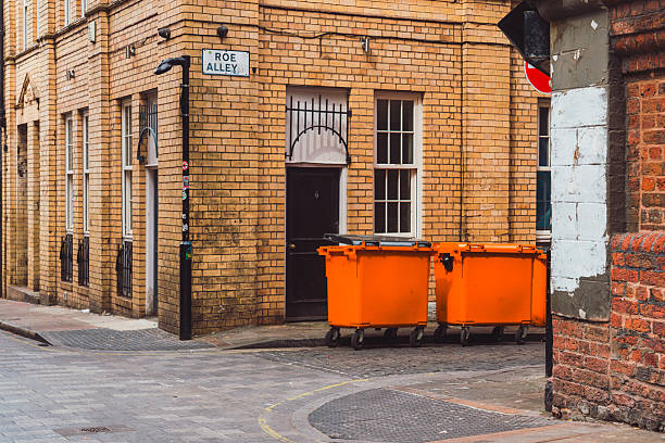 A group of different color waste wheelie bins outside on the street.